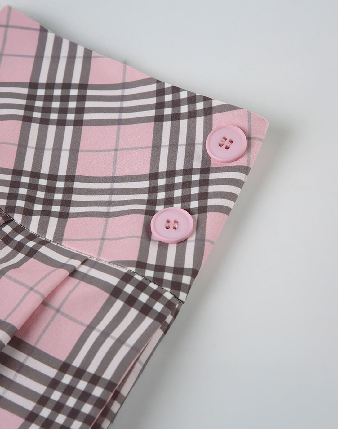 Decorative side buttons on the waistband, a charming detail that enhances the skirt's preppy, coquette look.