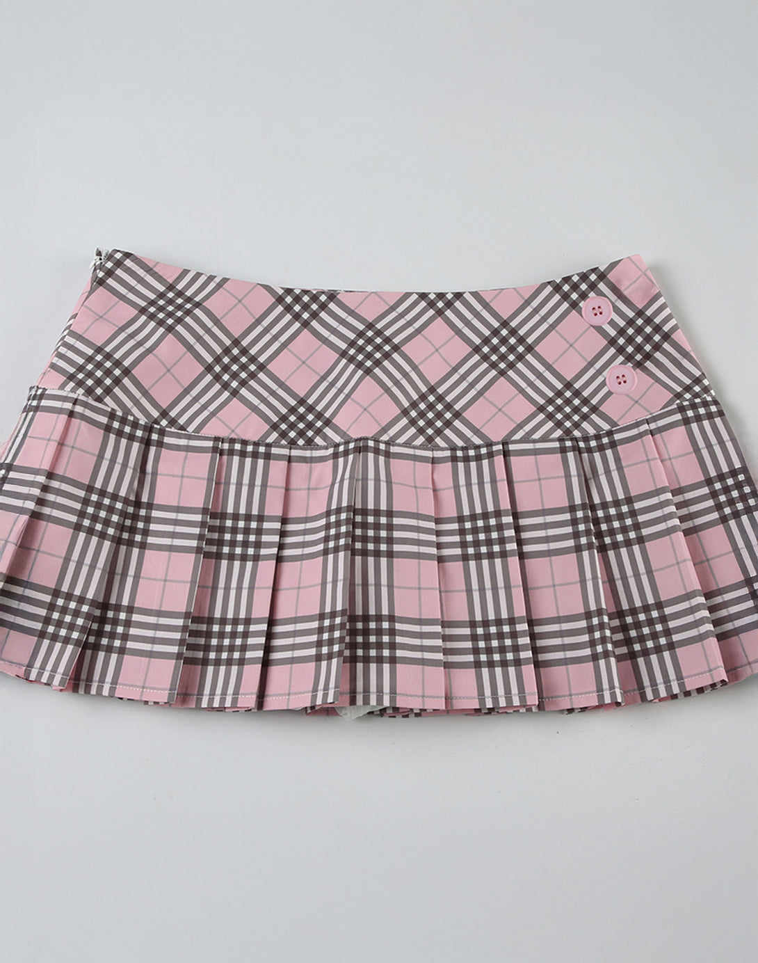 Angled view of the pink tartan mini skirt, highlighting the texture of the pleats. Embrace hyper feminine fashion.