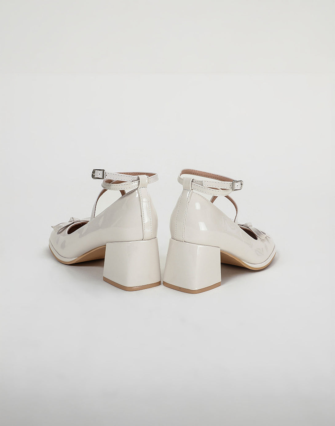 back view of ivory dollette shoes showing ankle strap buckles and block heel silhouette