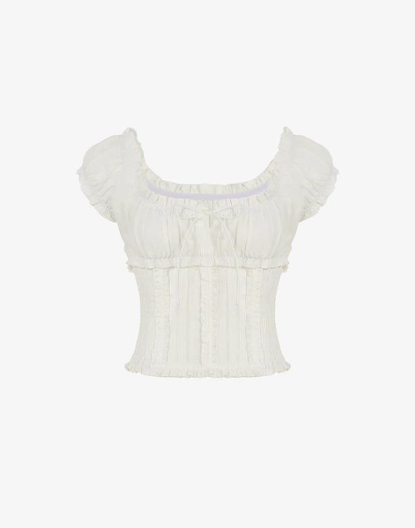 White coquette-style ruched top with puff sleeves, bow detail, and smocked body displayed on plain background.





