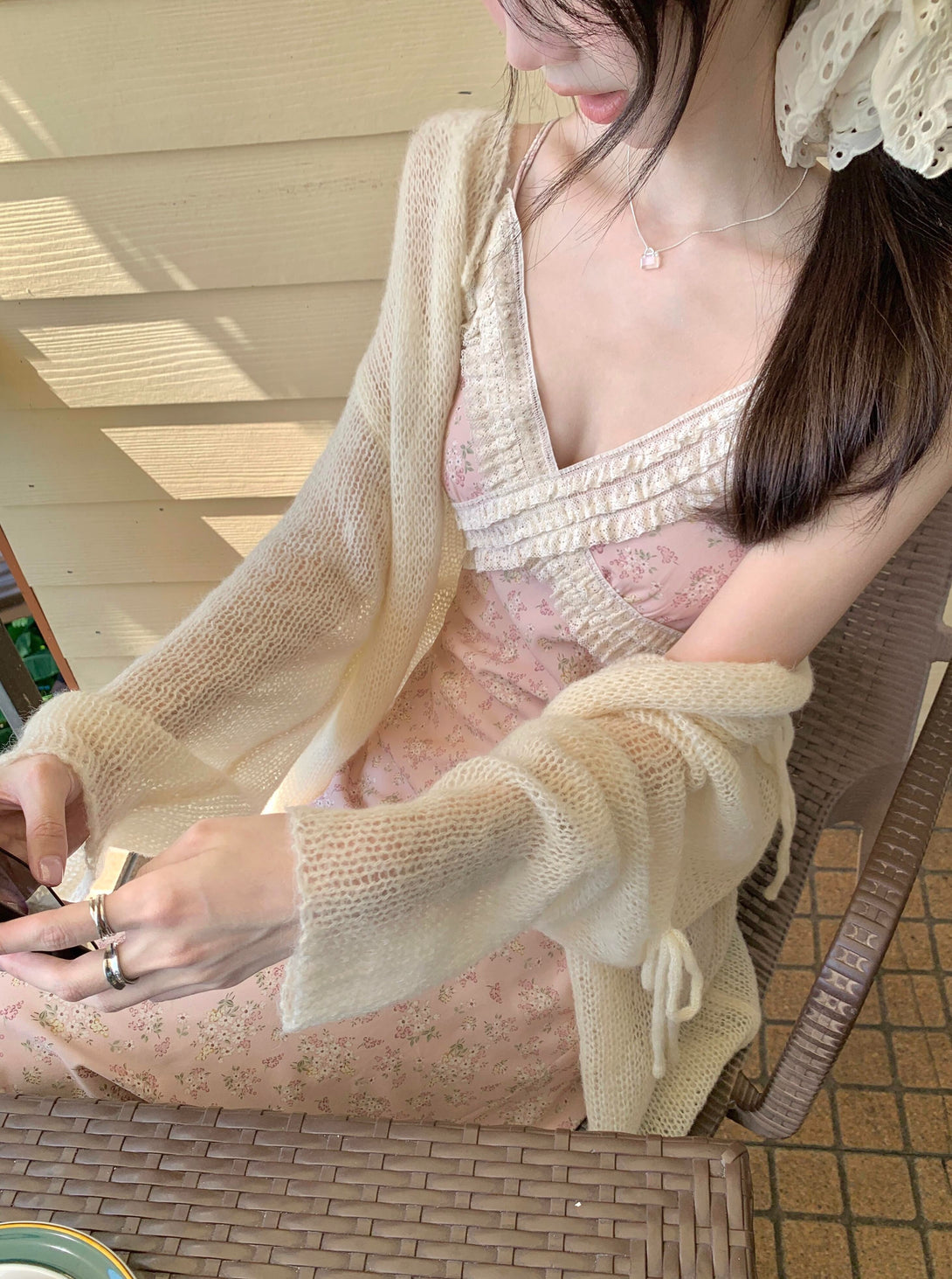 model styling pink floral midi dress with a cream sheer cardigan in soft natural lighting