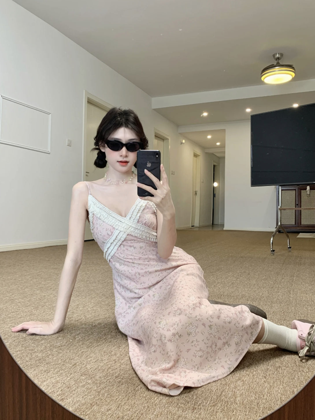 woman wearing coquette lace midi dress with sunglasses, seated on indoor carpeted floor