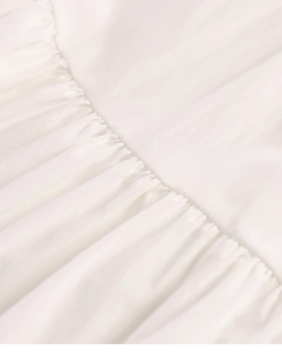 Detailed view of the gathered seam connecting the tiers on the white maxi skirt.