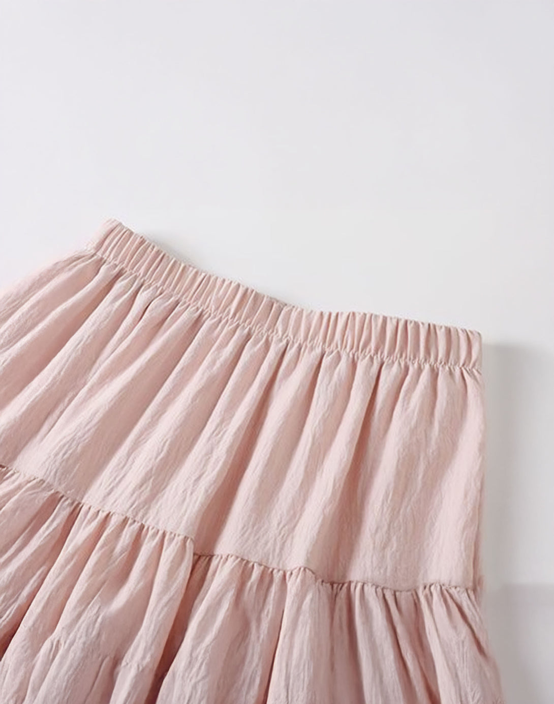Closeup of the comfortable, stretchy smocked waist on the pink tiered skirt.