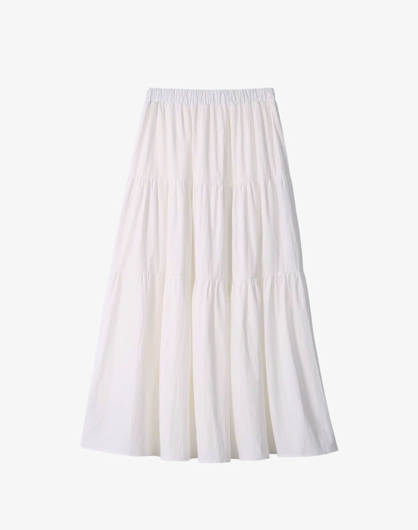 A studio shot of the white tiered maxi skirt, featuring a smocked waist and a long, flowy silhouette.