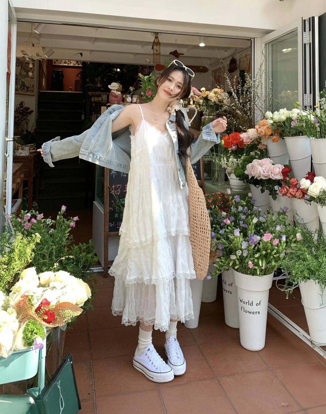 Model in a white tiered ruffle dress, perfect for hyper feminine and coquette aesthetic fashion, paired with sneakers for a casual, fresh look.