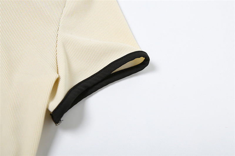 Close-up of sleeve edge with black piping on cream ribbed knit top