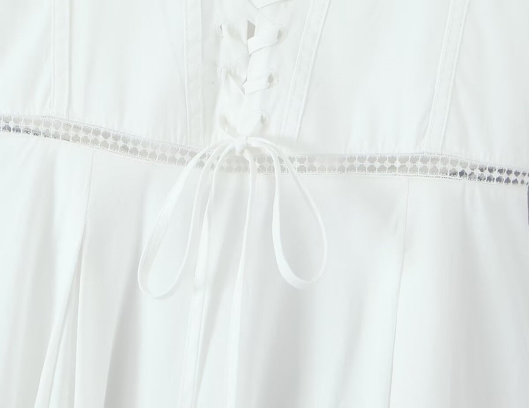 Close-up of a white coquette corset style dress lace-trimmed garment on a light gray background