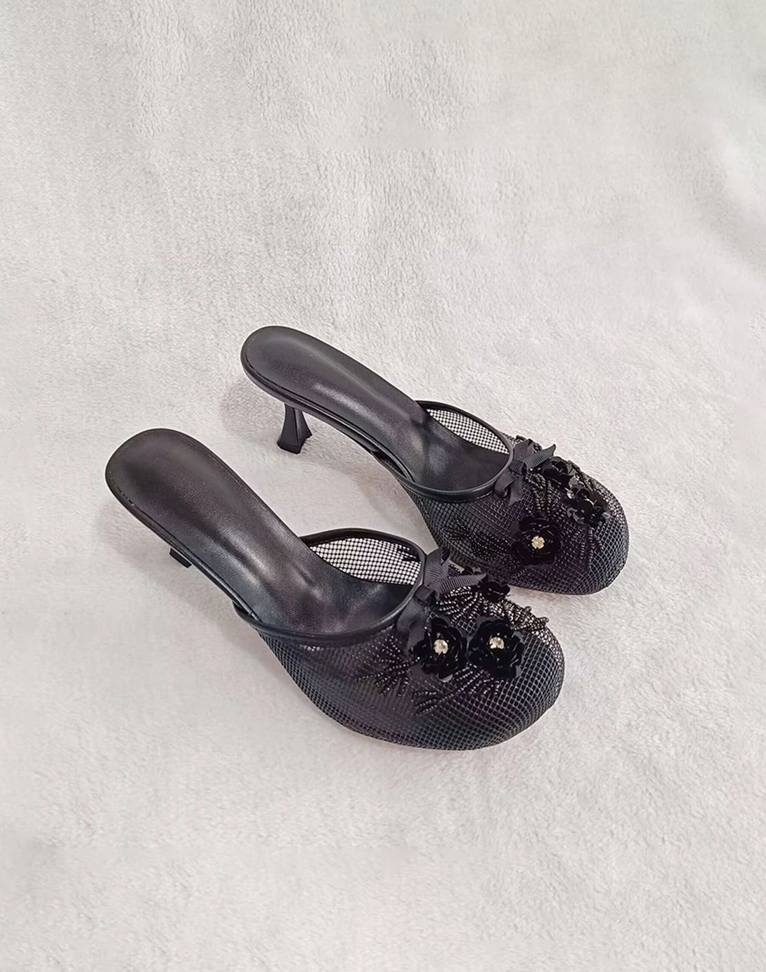 black mesh mules with kitten heels and floral embellishments, shown front and back views