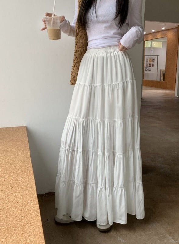 A model wearing the white long flowy skirt for a chic and elegant casual style look.