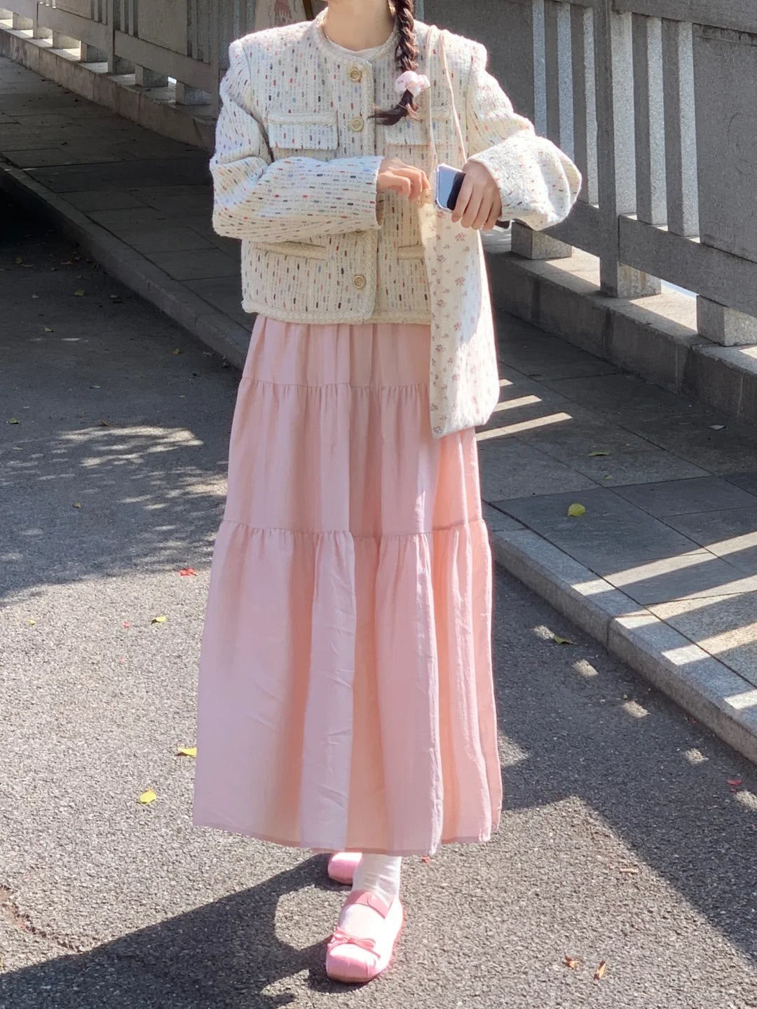 A woman styles the pink flared maxi skirt with a cardigan, showing its feminine fashion versatility.