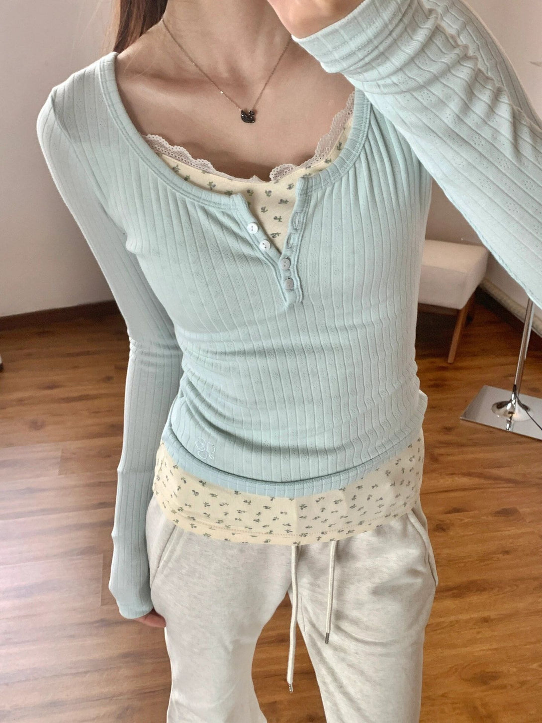 close-up of pastel blue layered henley top with ribbed texture and floral lace trim