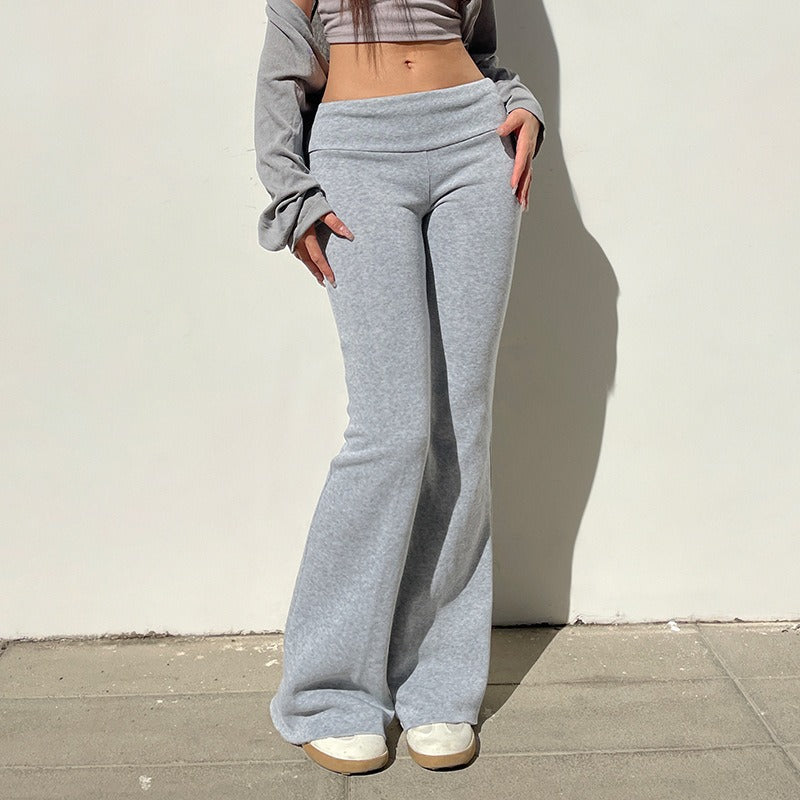 A model wearing the grey wide leg joggers with the waistband folded down for a Y2K low rise tracksuit bottoms style.