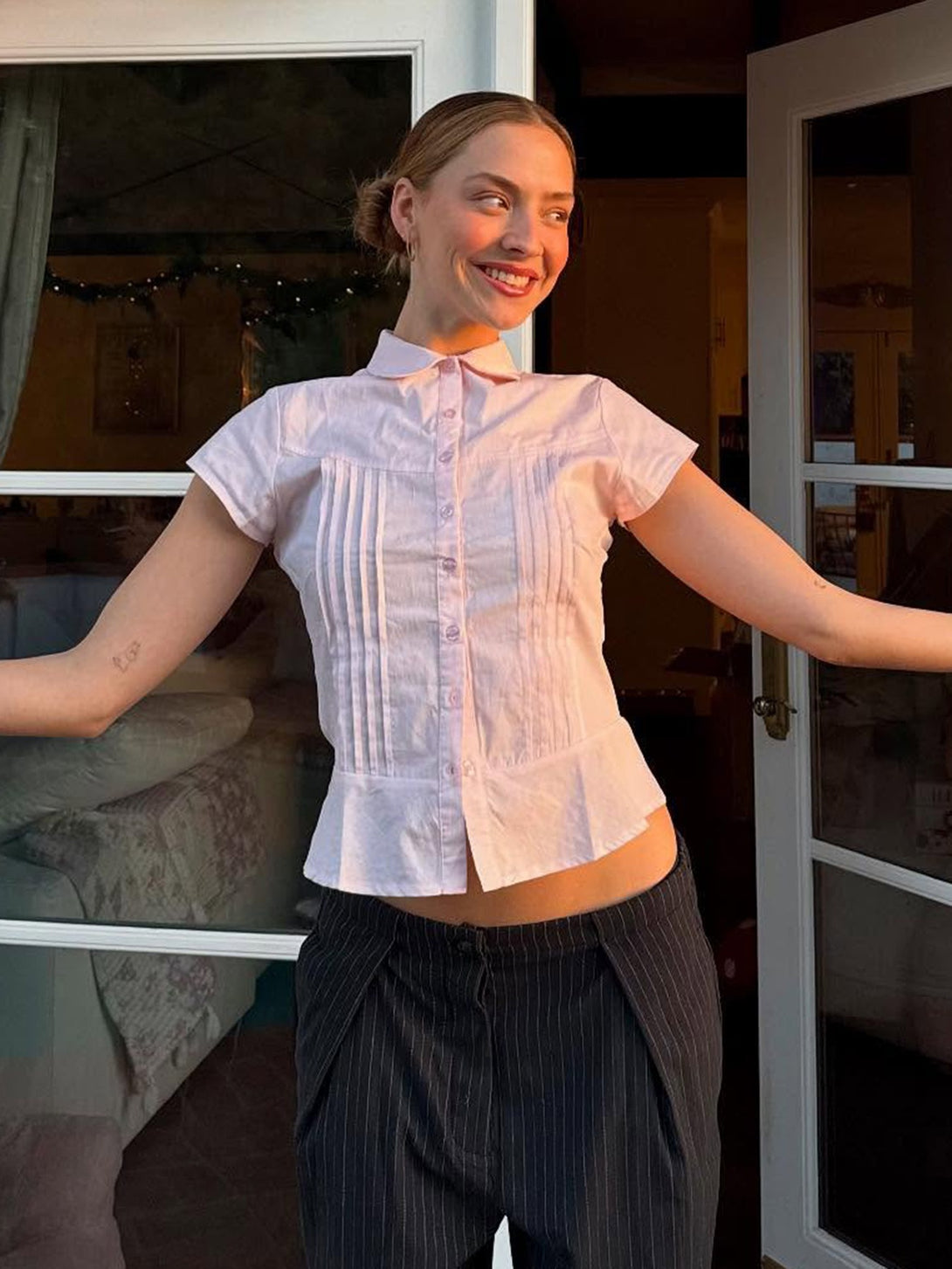 A woman models the pink pintuck blouse, styled for a smart casual look.